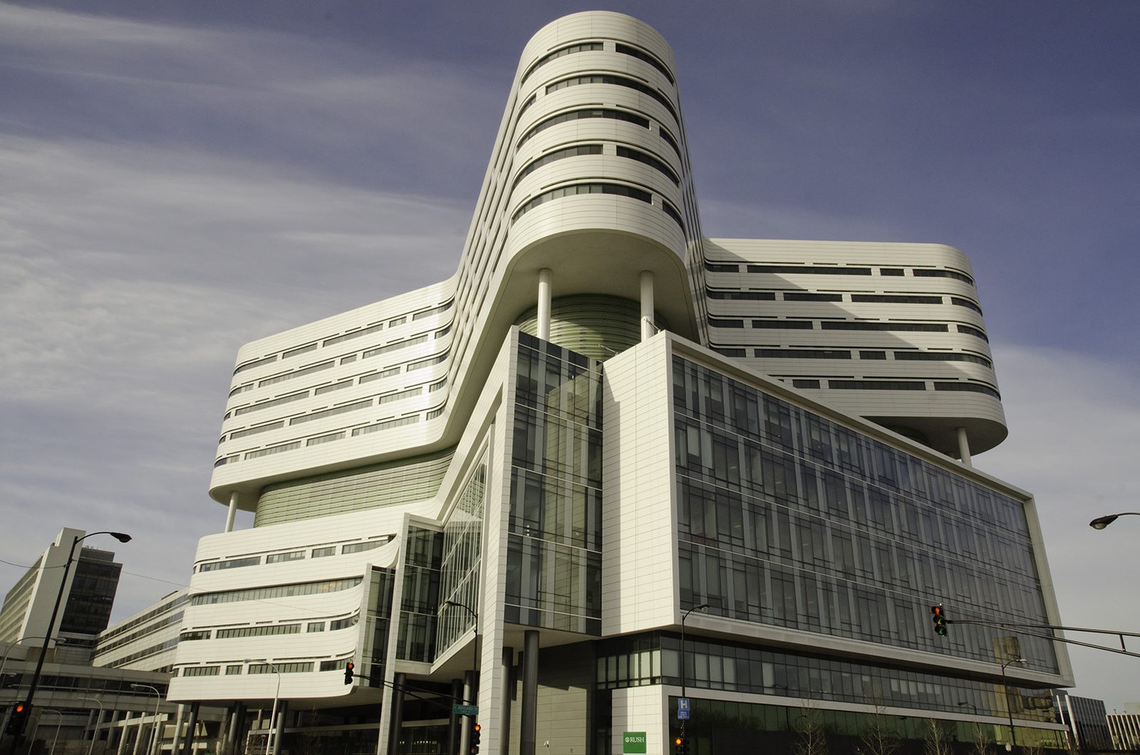 Curved white-and-glass Rush University Medical Center tower above a Chicago intersection.